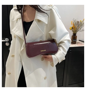 Close-up of deep wine red glossy underarm bag featuring a unique curved flap design