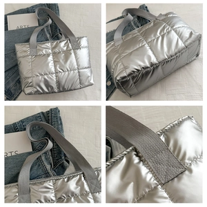 Close-up of silver quilted tote bag showing large square stitching and woven handles