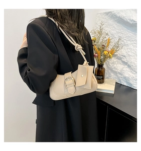 Detail of beige crescent bag with gold buckle and a small hanging coin purse on the strap