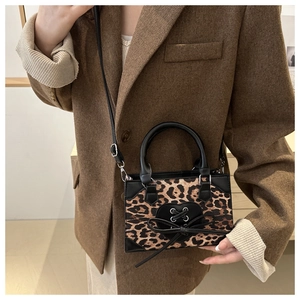 Detail of leopard print mini crossbody bag with black heart charm and bow decoration
