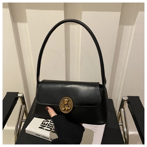 Detail of black matte leather baguette bag with vintage gold bear buckle on front