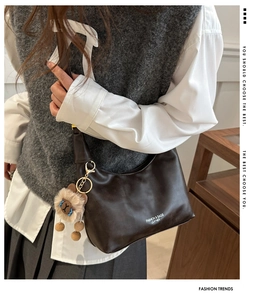 Détail du sac hobo marron foncé avec texture cuir et adorable breloque lion en peluche
