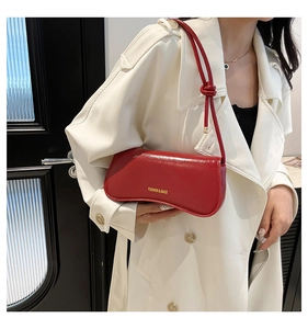 Primer plano de bolso de hombro rojo con nudo combinado con una gabardina crema