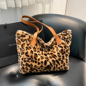 Chic leopard print faux fur tote bag with brown leather handles on a black leather chair