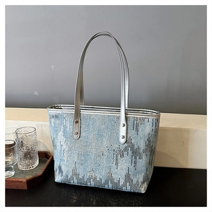 Detail of light blue sequin tote bag showing zigzag pattern and silver handle rivets