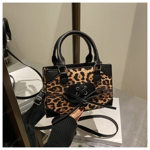 Close-up of leopard print mini tote bag featuring black heart bow and leather handles