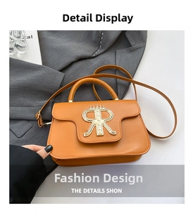 Makro-Detail einer orangen Lederumhängetasche mit goldenem Logo und verstellbarem Gurt