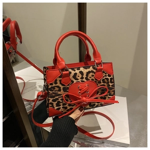 Detail of leopard print mini crossbody bag with red leather heart bow and metal chain