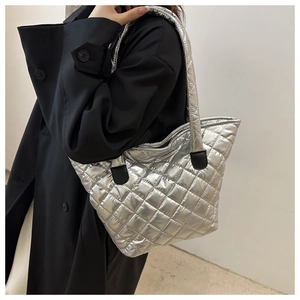 Detail of silver quilted tote bag showing metallic down fabric and handle attachment