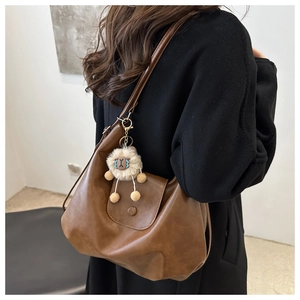Detail of a brown vintage tote bag with a soft leather texture and a plush lion charm