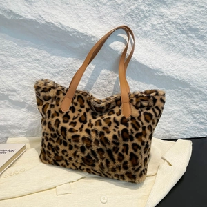 Plush leopard print faux fur tote bag with brown leather handles on a beige suit