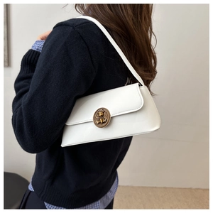 Detail of white underarm bag featuring a vintage gold bear-embossed metal buckle