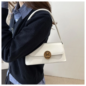 Detail of white leather shoulder bag with vintage golden bear relief buckle and retro style