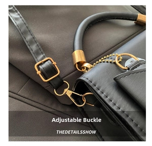 Detail of golden adjustable metal buckle and leather handle on black skull crossbody bag