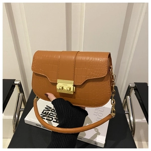 Detail of brown crocodile pattern shoulder bag with gold hardware and chain strap