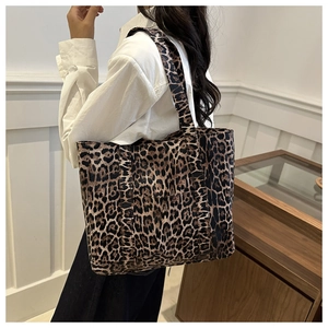 Detail of a large leopard print tote bag showing thick canvas texture and wide strap