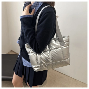 Detail of silver metallic quilted tote bag with large square patterns and woven handles