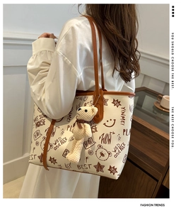 Detail of bear print tote bag with brown leather straps and a cute plush bear charm