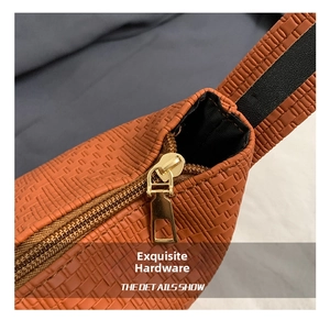 Detail eines goldenen Metallreißverschlusses an einer orangebraunen gewebten Tasche