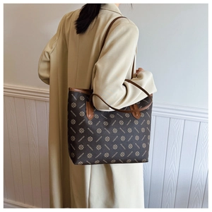 Detail of dark brown tote bag with gold floral patterns and premium leather strap