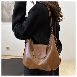 Detail of dark brown leather hobo bag with adjustable strap on model's shoulder