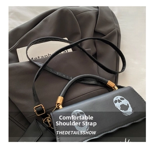 Detail of skull print handbag with gold hardware on a gray textured suit jacket