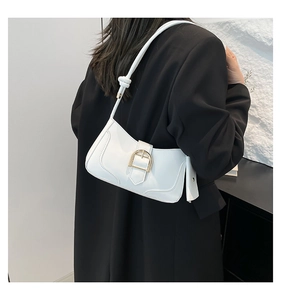 Detail of white crescent underarm bag with gold buckle and knotted strap on shoulder