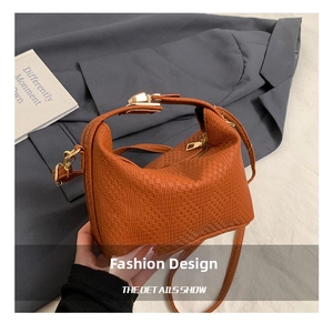 Detail der orange-braunen Kissentasche mit Goldbeschlägen und Webmuster-Prägung