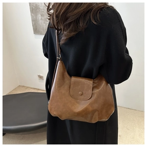 Retro brown crossbody bag with matte faux leather worn over a black winter coat