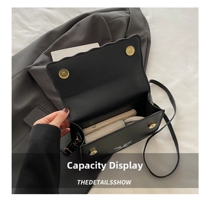Internal view showing capacity of black crossbody bag with skull print on gray fabric