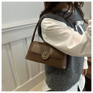 Detail of vintage brown leather bag with crown bear metal buckle on model