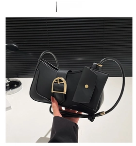 Detail of black crescent shoulder bag featuring a gold horseshoe buckle and small coin purse