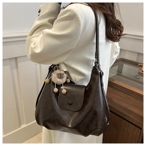 Detail of dark brown tote bag in faux leather with lamb pendant and snap button closure