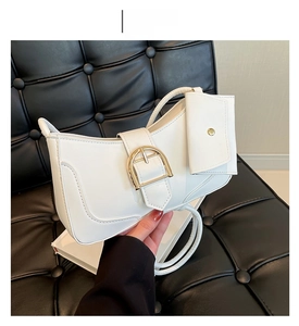 Detailed shot of white leather crescent bag with gold horseshoe buckle and small pouch