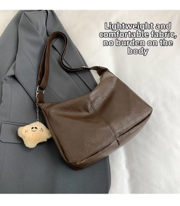 Detail of dark brown vintage pleated leather tote bag with a plush bear pendant
