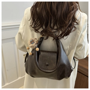 Detail of dark brown leather tote with flap closure and cute lion plush pendant