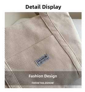 Close-up of beige corduroy fabric with Fashion Instinct woven label and vertical texture