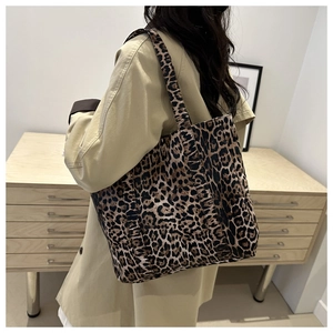 Detail of a large leopard print tote bag worn with a beige coat in a minimalist setting