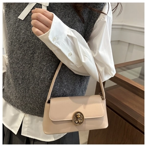 Detailed view of vintage beige underarm bag featuring a golden teddy bear relief clasp