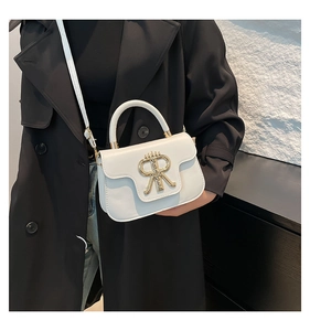 Details der weißen Leder-Umhängetasche mit goldenem RM-Logo und mattem Finish am Verschluss