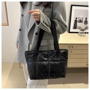 Close-up of quilted black puffer tote bag showing soft texture and square stitching pattern