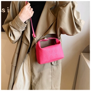 Détail d'un sac à main fuchsia texturé porté avec un trench-coat classique beige élégant