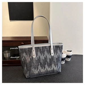 Detailed view of silver sequin wave patterns on a high-capacity tote bag with silver straps