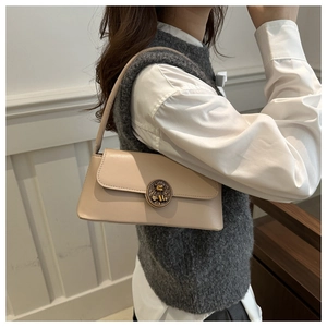 Detail of a vintage cream baguette bag featuring a bronze bear relief buckle and shoulder strap