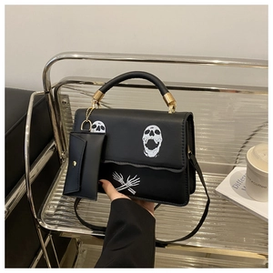Detail of gothic black leather shoulder bag with white skull print and matching mini pouch