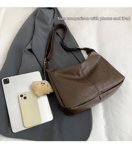 Retro brown leather hobo bag size comparison with an iPad and a smartphone on a gray blazer