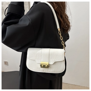 Detail of white crocodile pattern bag featuring gold buckle and metal chain strap on model
