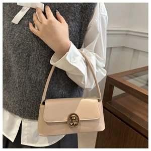Detail of vintage cream shoulder bag featuring an embossed golden cat buckle closure