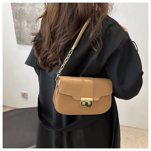 Detail der kamelfarbenen Kroko-Tasche mit goldener Schnalle und Kettenriemen am Modell