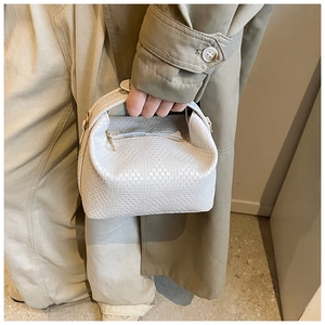 Nahaufnahme der weißen Handtasche mit Flechtmuster und Goldreißverschluss am Model